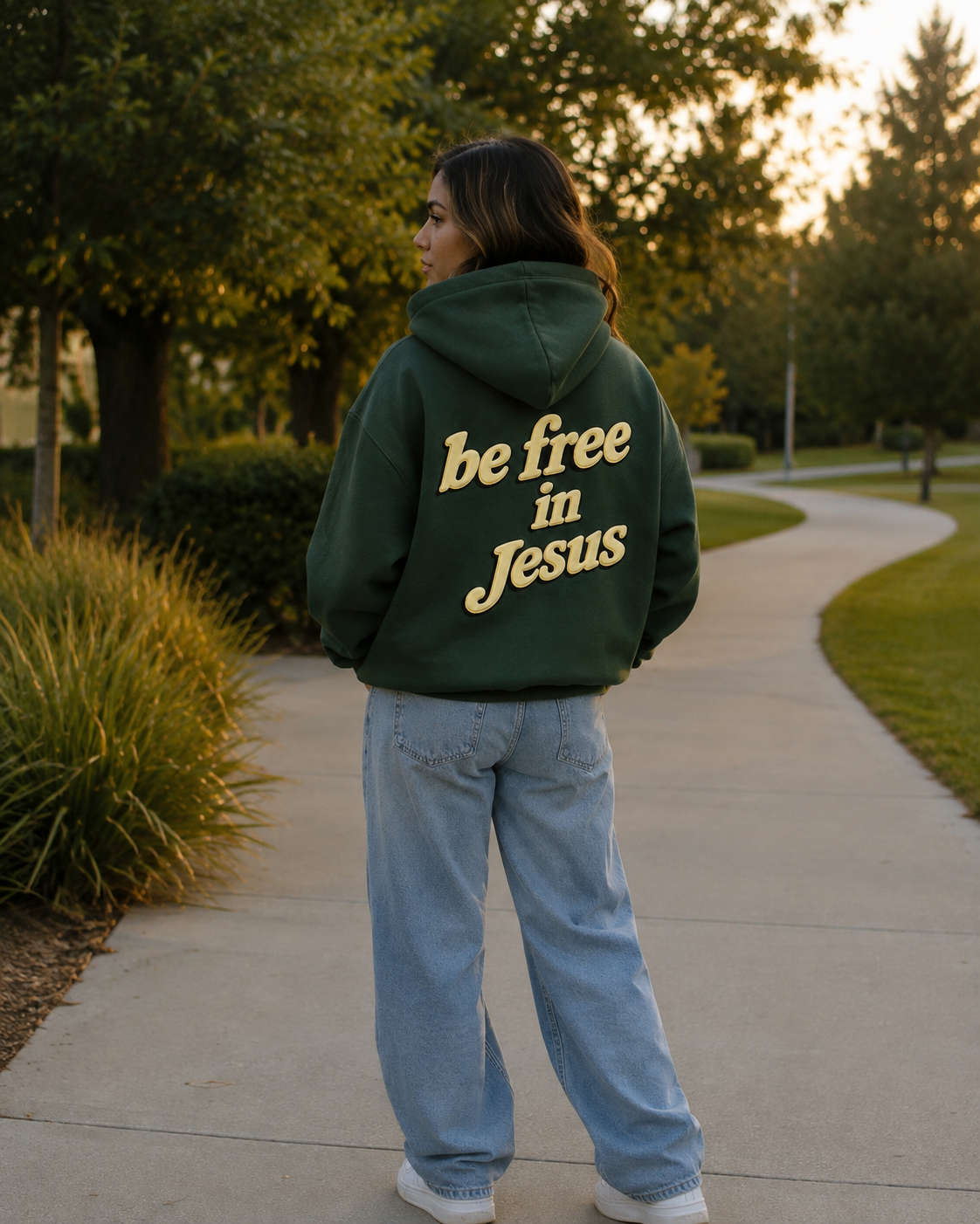 Woman wearing Be Free in Jesus hoodie from behind in park